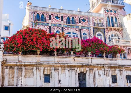 Bougainvillea coloré se décale sur le balcon d'un bâtiment blanc décoratif en carrelage à Lisbonne, au Portugal, sous le ciel bleu Banque D'Images