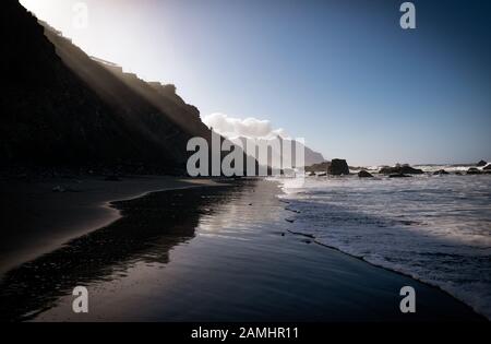 De hautes falaises jette une ombre profonde sur misty Benijo beach (La plage de Benijo) dans le parc rural d'Anaga sur la côte nord de Tenerife, Îles Canaries. Banque D'Images