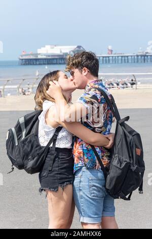 Jeune couple baiser sur la promenade de la plage, Blackpool, Lancashire, Angleterre, Royaume-Uni Banque D'Images