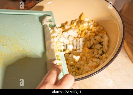 Faites cuire les mains pour hacher les œufs et les pommes de terre pour la salade. Nourriture végétarienne saine et naturelle Banque D'Images