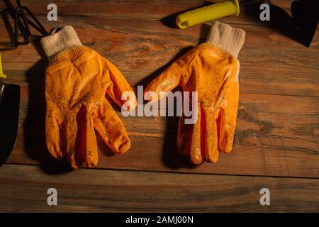 Utilisez des gants de jardin sales sur le fond de la table en bois. Banque D'Images