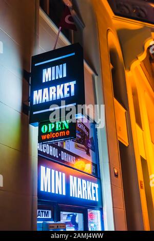 Signez à l'extérieur d'un mini-marché la nuit, publicité de nourriture, alcool, boissons, tabac et articles essentiels. Banque D'Images