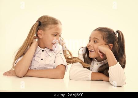 Faire de nouveaux amis à l'école. Heureux les petits amis parler en classe. Les amis de l'école peu souriant pour chaque autre isolé sur blanc. Adorable girl friends bénéficiant de bonnes relations d'amitié. Banque D'Images