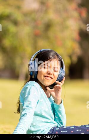 Petite fille d'écouter de la musique sur le smartphone avec ses écouteurs dans le parc Banque D'Images