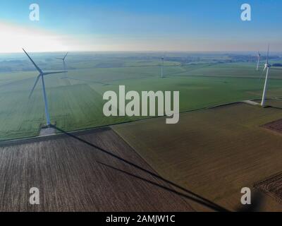 Vue aérienne des éoliennes sur les champs agricoles pendant la journée hivernale bleue. Production d'énergie avec des énergies propres et renouvelables. Banque D'Images