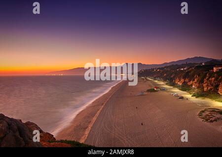 Une vue panoramique sur l'océan et la plage au crépuscule. Remarquez le stationnement et la rangée de lumières de rue Banque D'Images