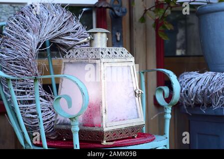 Noël et hiver encore la vie avec une ancienne lanterne romantique, qui a des panneaux glacés congelés, sur une chaise devant une porte en bois avec une couronne Banque D'Images