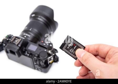 Main de l'homme tenant la carte XQD sur fond blanc. Banque D'Images