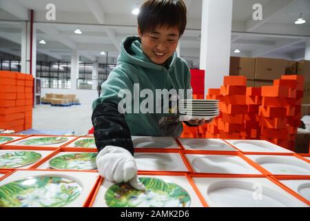 (200114) -- JINGDEZHEN, le 14 janvier 2020 (Xinhua) -- un travailleur emballe des plaques de céramique conçues par Wu Anran et présentant l'année chinoise du rat à Jingdezhen, dans la province du Jiangxi en Chine orientale, le 9 janvier 2020. Jingdezhen, également connu sous le nom de "capitale de la Porcelaine", est célèbre pour son savoir-faire en céramique élaboré qui exige un processus de production extrêmement compliqué. Par le passé, de nombreux concepteurs de porcelaine jeunes, compétents et ambitieux pourraient créer de bons modèles, mais avaient du mal à compléter de manière indépendante la production et les ventes. D'autre part, les entreprises traditionnelles qui pourraient faire de la production et Banque D'Images