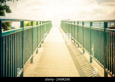 pont entouré de rampes métalliques jusqu'à un ciel éclairé Banque D'Images