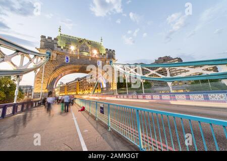 Les touristes et les sentiers de lumière de voiture la nuit le long de Tower Bridge, Londres en été. Banque D'Images