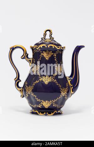 Gros plan d'une magnifique théière en porcelaine vintage bleu cobalt avec motif fleuri doré sur fond blanc Banque D'Images