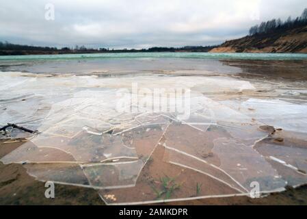 Morceaux de glace fine sur l'eau d'une carrière de sable. Région de Leningrad. Russie. Banque D'Images