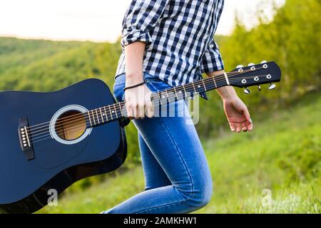 belle fille posant près d'une guitare noire Banque D'Images