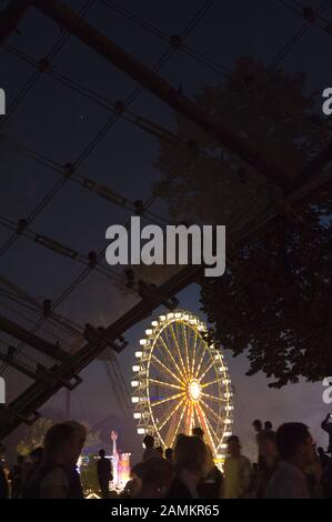 La roue géante Ferris illuminée la nuit au festival d'été Impark dans le parc olympique de Munich. [traduction automatique] Banque D'Images