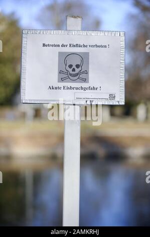 Panneau d'avertissement avec crâne et os croisés et l'inscription 'pas de trespassing sur la patinoire. Danger aigu d'un œuf cassé!' au Nymphenburger Kanal de Munich. Là, le programme de sports d'hiver est annulé cette année parce que la glace n'est pas assez épaisse. [traduction automatique] Banque D'Images