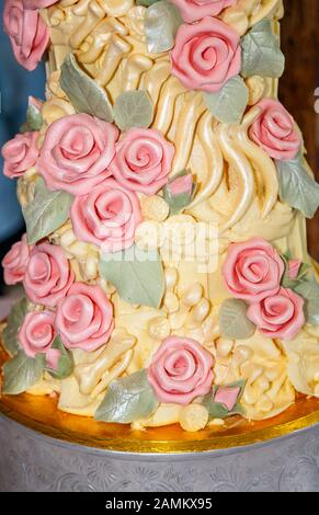 Gâteau de mariage au chocolat glacé aux couleurs élaborées avec os de dinosaures à glaçage jaune et roses à sucre rose fabriqués par Choccywoccydoodah de Brighton Banque D'Images