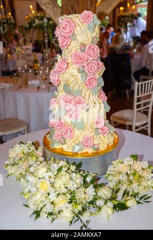 Gâteau de mariage au chocolat glacé aux couleurs élaborées avec os de dinosaures à glaçage jaune et roses à sucre rose fabriqués par Choccywoccydoodah de Brighton Banque D'Images