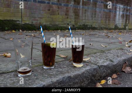 Trois verres, un vide et deux presque complets, ont été laissés dans la rue, le matin après la Saint-Sylvestre, le 1 janvier 2019, dans le sud de Londres, Angleterre. Banque D'Images