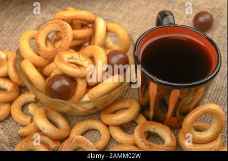 Bagels, petits chocolats, une tasse de thé et un tissu de fabrication locale sur un fond de bois close-up Banque D'Images