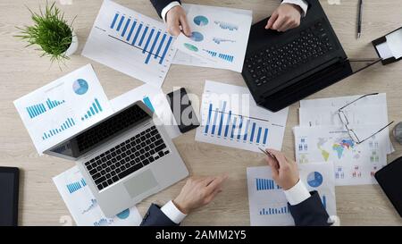Auditeurs vérifiant les documents commerciaux de l'entreprise, travaillant sur des ordinateurs portables, vue de dessus Banque D'Images