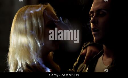 Homme ivre éclairage cigarette pour la jolie femme dans la rue de nuit, connaissance Banque D'Images