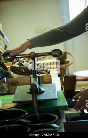 Saddler Beate Bader travaillant sur la machine à poinçonner dans son atelier à Aschheim près de Munich. [traduction automatique] Banque D'Images