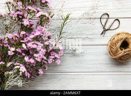 Fleuriste lieu de travail: Fleurs et accessoires sur une table en bois blanc. Pose plate. Banque D'Images