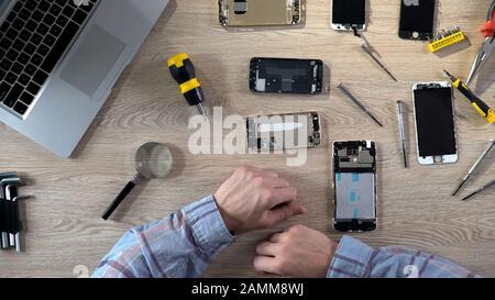 Homme répare un gadget cassé, diagnostic des problèmes de téléphone mobile, centre de service Banque D'Images