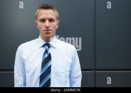 Portrait of a serious businessman standing against the wall moderne regardant la caméra avec une expression vide Banque D'Images