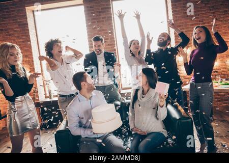 Photo de groupe des amis pour célébrer l'organisation de parti de bébé de surprise les futurs parents s'asseoir sur le canapé apporter grand gâteau confettis tombant restaurant formel usure Banque D'Images