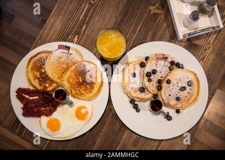 La succursale de M. Pancake sur Emil-Riedel-Straße vient d'ouvrir ses portes. Dans la nouvelle branche, différentes variantes de crêpes sont offertes : crêpes au bacon, sirop d'érable, œufs frits et drapeau américain (à gauche) et crêpes aux bleuets et au sirop d'érable (à droite), servies avec du jus d'orange fraîchement pressé. [traduction automatique] Banque D'Images