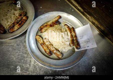 Le restaurant traditionnel de Munich 'Nürnberger Bratwurst Glöckl am Dom', enregistré à l'année de son 125ème anniversaire. Dans les saucisses fritures avec sauerkraut, servies sur une plaque d'étain. [traduction automatique] Banque D'Images