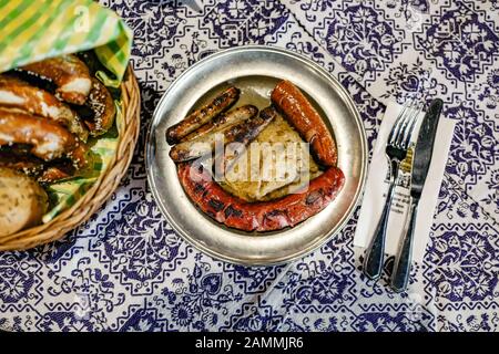 Le restaurant traditionnel de Munich 'Nürnberger Bratwurst Glöckl am Dom', enregistré à l'année de son 125ème anniversaire. Dans les saucisses fritures avec sauerkraut, servies sur une plaque d'étain. [traduction automatique] Banque D'Images