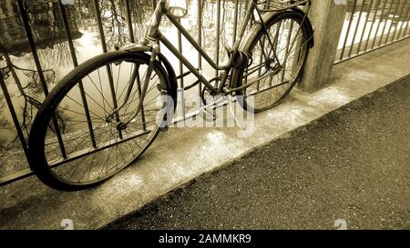 Vélo rétro debout près de la rivière attaché à la clôture, véhicule ancien Banque D'Images