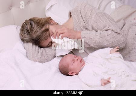 Jeune maman avec un bébé souffrant de dépression post-natale, pleurer dans un mouchoir, allongé sur un lit Banque D'Images