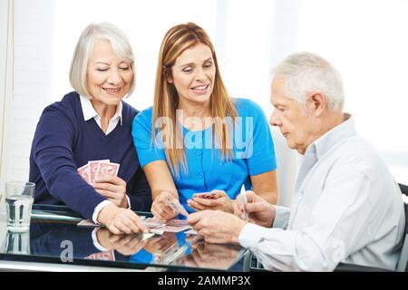 Famille avec aînés jouant des cartes dans la maison de soins infirmiers ensemble Banque D'Images