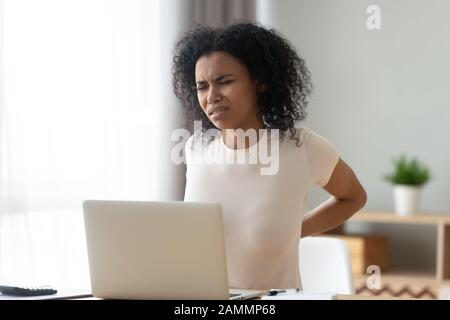 Femme africaine après ordinateur portable longue utilisation ayant moins de mal au dos Banque D'Images