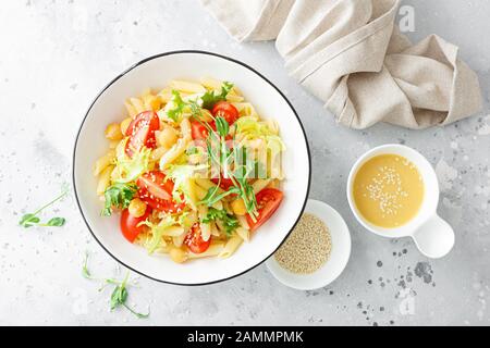 Salade de pâtes avec tomates fraîches, pois chiches, laitue et pousses de pois dans le bol du déjeuner Banque D'Images