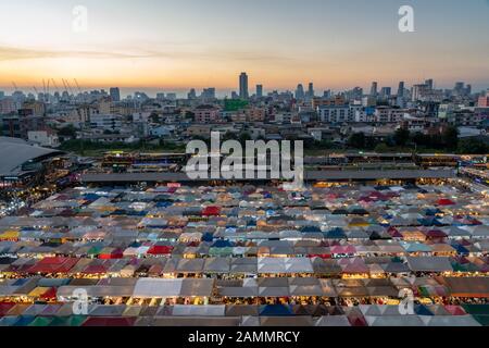 Vue sur le coucher du soleil sur le marché de nuit du train Ratchada. Le marché de nuit du train Ratchada, également connu sous le nom de Talad Nud Rod Fai, est une nouvelle place de marché aux puces à Bangkok Banque D'Images