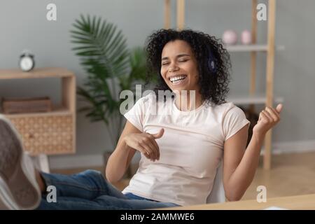 Femme africaine assise au bureau dans un casque imitant la guitare de jeu Banque D'Images