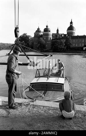 Seeblick auf Schloss Gripsholm am See Mälaren mit Boot und Männern am Anlegeplatz, bei Stockholm, Schweden, 1969. Vue sur le lac du château de Gripsholm sur le lac Mälaren avec bateau et hommes à amarrer, près de Stockholm, Suède, 1969. Banque D'Images