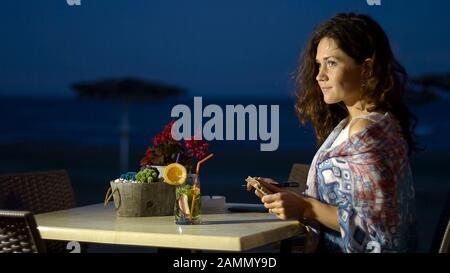 Bonne jeune femme tenant un journal intime avec des souvenirs romantiques, détendez-vous au bord de la mer Banque D'Images