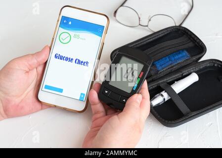 Mesure des niveaux de glucose et utilisation d'un smartphone. Santé et concept médical Banque D'Images