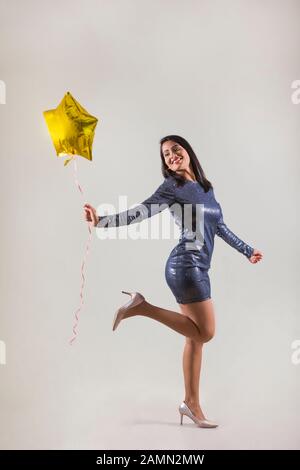 Belle femme dans une tenue de fête tenant un ballon en forme d'étoile. Banque D'Images