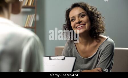 Jeune femme heureuse parlant avec le psychologue à la clinique, séance de rééducation Banque D'Images
