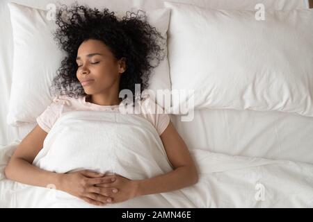 Une femme africaine dormant se trouve sur la moitié du lit Banque D'Images