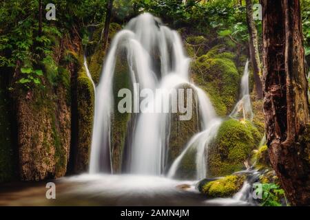 Chute d'eau à exposition prolongée sur des roches brunes et vertes filmées dans les lacs de Plitvice, Croatie. Banque D'Images