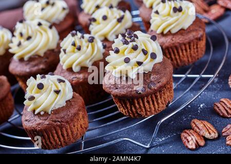 Gros-plan de cupcakes au chocolat accompagnés de givrage à la crème de beurre à la vanille sur un porte-gâteaux en métal sur une table en béton, vue horizontale de dessus Banque D'Images