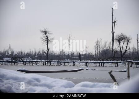 Un homme de Kashmiri marche sur un pont en bois recouvert de neige après une chute de neige fraîche à Srinagar.En Raison de la forte chute de neige au cours des 48 dernières heures, il y a eu plusieurs avalanches dans lesquelles au moins 4 soldats de l'armée indienne et 5 civils Tués au Cachemire administré par l'Inde. Banque D'Images